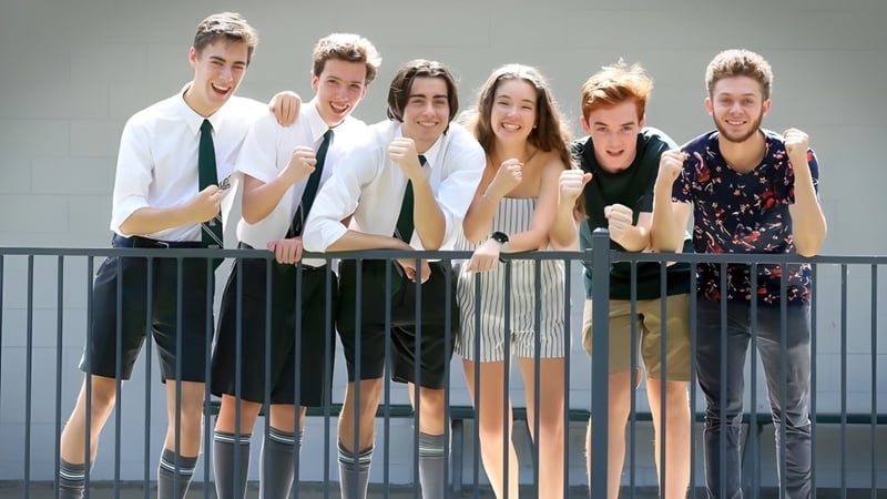 Eine Gruppe Schülerinnen und Schüler der The Gap State High School steht vor grauem Hintergrund und lächelt in die Kamera.