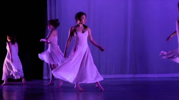 Schüler der The Governor's Academy tanzen auf einer Bühne vor einem violetten Hintergrund.