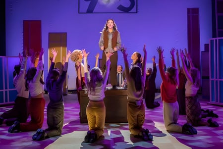 Eine Gruppe von Schülerinnen und Schülern steht mit erhobenen Armen in einem Flur der The Hammond School unter violettem Licht.