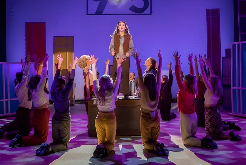 Eine Gruppe von Schülerinnen und Schülern steht mit erhobenen Armen in einem Flur der The Hammond School unter violettem Licht.