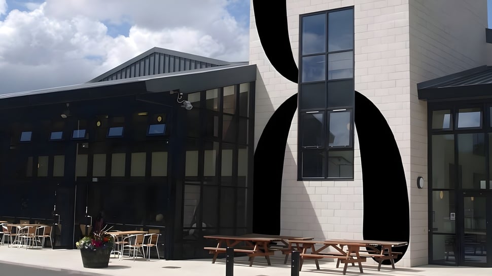 Das moderne mehrstöckige Gebäude der The Hammond School mit Außenbereich und Holzsitzmöbeln.