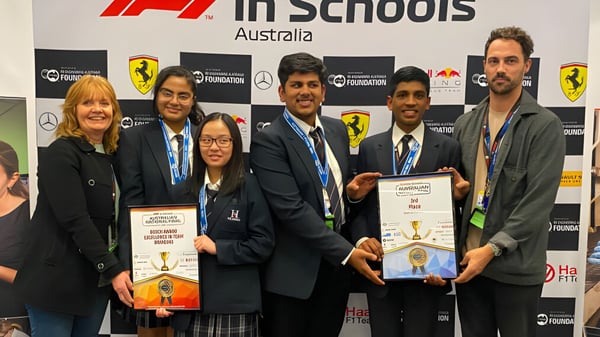 Schüler und Erwachsene der The Heights School stehen zusammen bei der F1 in Schools Preisverleihung vor einem Logo-Hintergrund.