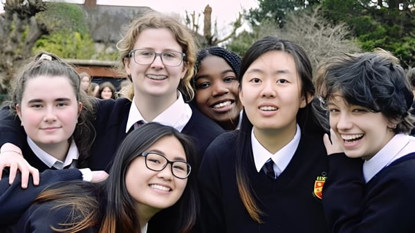 Eine Gruppe lächelnder Schülerinnen und Schüler der The High School steht im Freien zusammen vor Bäumen und Gebäuden.