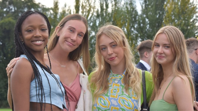 Eine Gruppe von vier Schülerinnen posiert gemeinsam im Grünen auf dem Gelände der The High School.