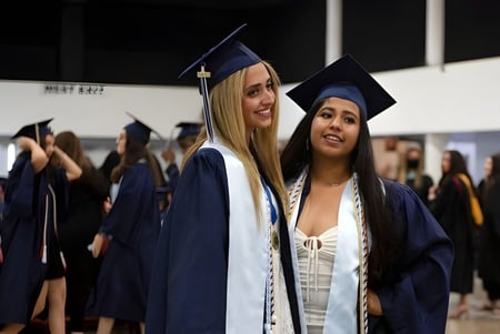 Zwei Absolventinnen der The Hills Grammar School stehen gemeinsam im Saal während der Abschlussfeier.