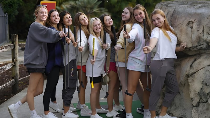 Eine Gruppe Schülerinnen steht gemeinsam draußen vor einem felsigen Hintergrund auf dem Campus der The King's Academy.