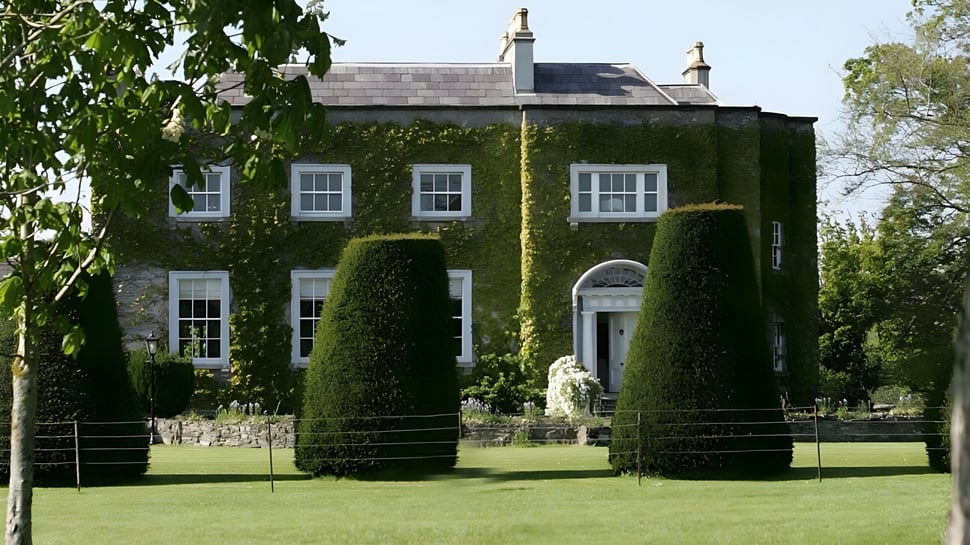 Das Anwesen von The Kings Hospital ist von gepflegtem Grün und einem schmiedeeisernen Zaun umgeben.