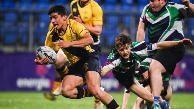 Ein Rugbyspiel mit Spielern in gelben und grünen Trikots während eines Tacklings auf dem Spielfeld der The Kings Hospital.