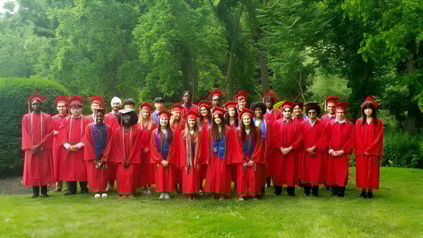 Eine Gruppe von Absolventen der The Knox School steht im Freien inmitten grüner Bäume.