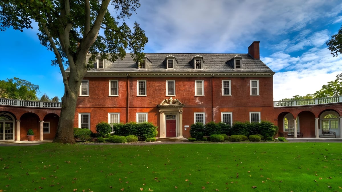 Das Herrenhaus der The Knox School steht umgeben von gepflegtem Rasen und hohen Bäumen unter blauem Himmel.