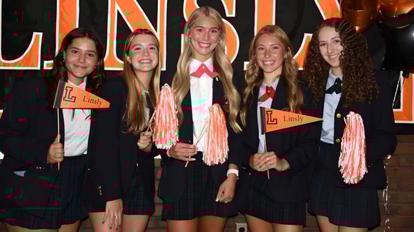 Eine Gruppe von Schülerinnen der The Linsly School steht in schwarzen Uniformen mit pinken Akzenten vor einem großen Lindy-Schild und hält pinke Pompons.