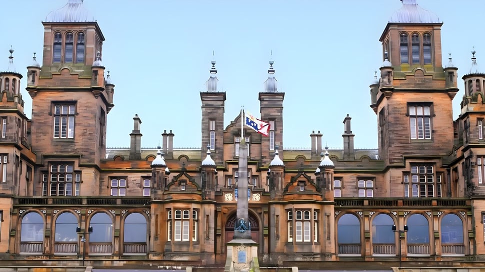Das historische Gebäude der The Mary Erskine School mit Türmen und Bögen vor klarem Himmel.