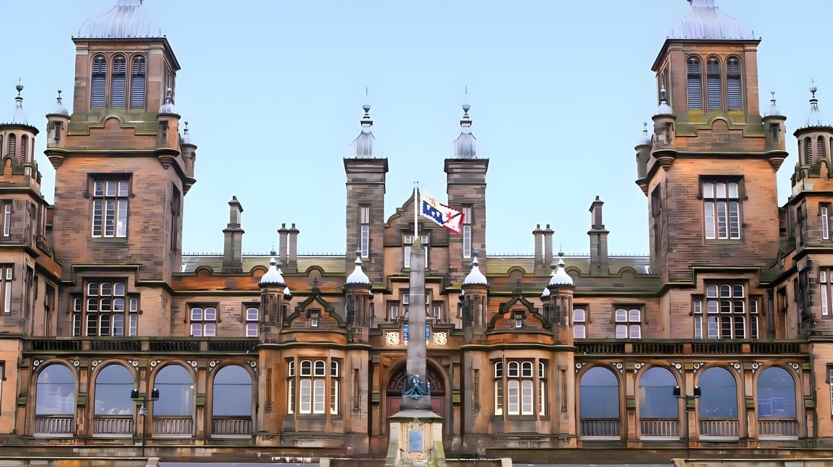 Das historische Gebäude der The Mary Erskine School mit Türmen und Bögen vor klarem Himmel.
