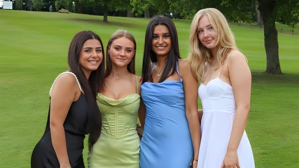 Vier Schülerinnen der The Mary Erskine School stehen im Park auf einer Wiese vor Bäumen.