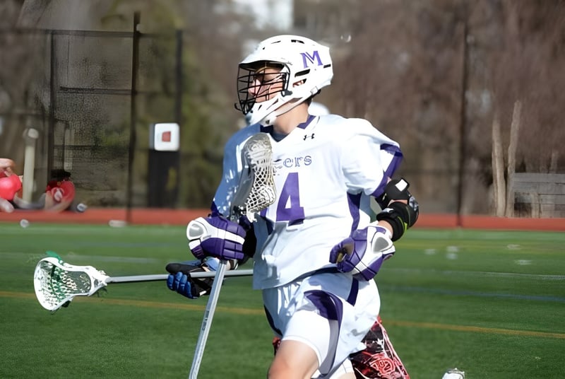 Ein Lacrosse-Spieler mit der Nummer 4 in weißer Uniform auf dem Sportplatz der The Masters School.