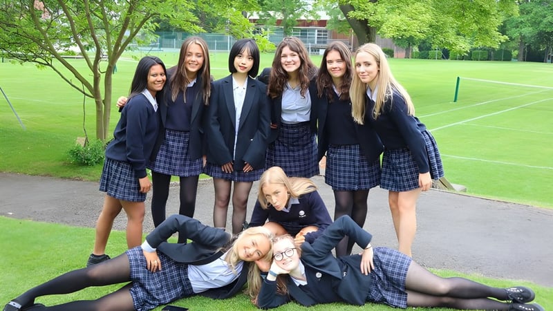 Eine Gruppe Schülerinnen der The Mount School York steht auf einer Wiese vor Bäumen.