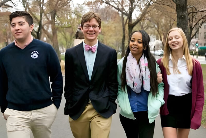 Vier Schülerinnen und Schüler der The Newman School gehen gemeinsam eine von Bäumen gesäumte Straße entlang.