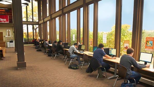 Arbeitsplatz mit mehreren Schülern am Computer in einem großen Raum der The Orme School mit Blick auf die Natur.