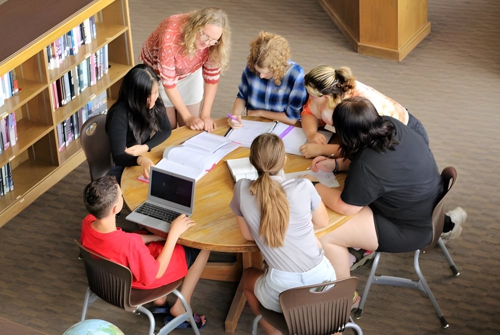 Schüler der The Orme School sitzen an einem Tisch in der Bibliothek und arbeiten gemeinsam an einer Aufgabe.