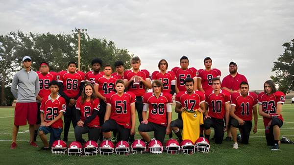 Eine Gruppe von Schülern der The Orme School steht in roten und schwarzen Sportuniformen auf einem Rasenfeld mit Bäumen im Hintergrund.