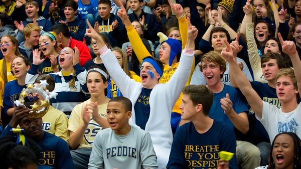 Viele Schülerinnen und Schüler der The Peddie School jubeln und heben die Arme bei einer Sportveranstaltung.