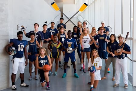 Eine Gruppe junger Athleten posiert gemeinsam in der Sporthalle der The Peddie School mit Sportausrüstung im Hintergrund.