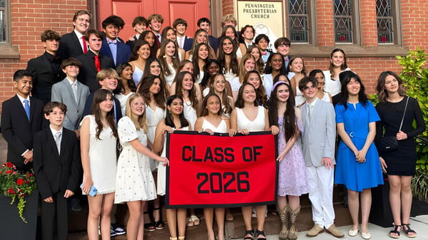 Eine Gruppe Schülerinnen und Schüler der The Pennington School steht in formeller Kleidung vor einem Backsteingebäude mit einem Banner der Klasse 2026.