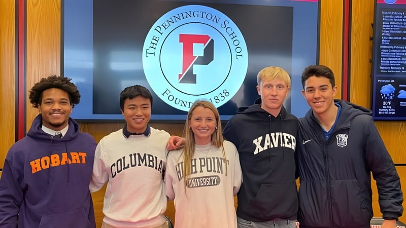 Eine Gruppe von fünf Schülerinnen und Schülern steht vor dem Logo der The Pennington School an der Wand.