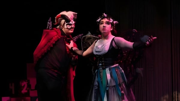 Zwei Personen in auffälligen Kostümen stehen auf der Bühne des The Pennington School Theaters.