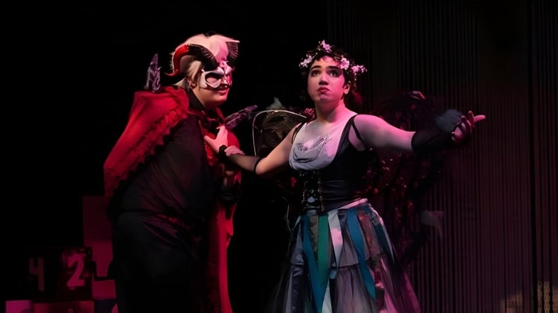 Zwei Personen in auffälligen Kostümen stehen auf der Bühne des The Pennington School Theaters.