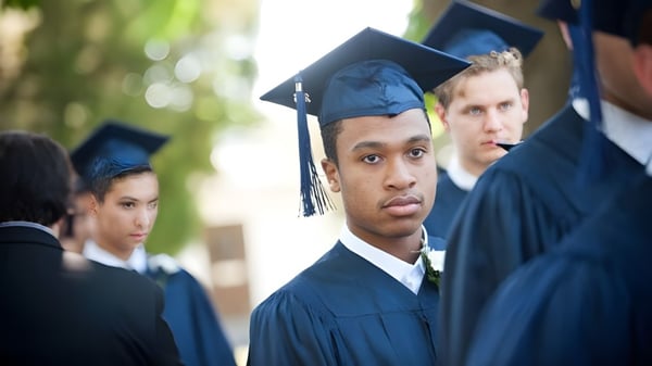Eine Gruppe von Absolventinnen und Absolventen der The Phelps School steht in schwarzen Talaren unter freiem Himmel vor Bäumen.