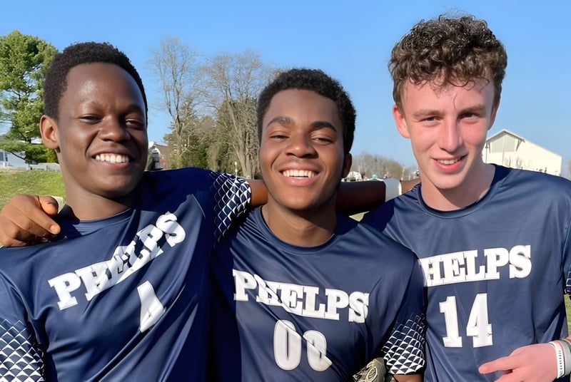 Drei Schüler der The Phelps School tragen Sporttrikots und stehen draußen vor Bäumen und Gebäuden.