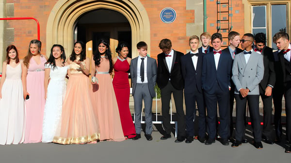 Eine Gruppe formell gekleideter Personen posiert vor einem verzierten Bogen auf dem Gelände der The Royal School Wolverhampton.