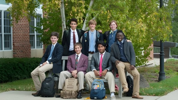 Eine Gruppe von Schülerinnen und Schülern steht auf einer Wiese vor einem Gebäude auf dem Campus der The Salisbury School.