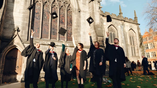 Eine Gruppe von Absolventinnen und Absolventen des The Sheffield College steht vor einer gotischen Kathedrale im Herbst.
