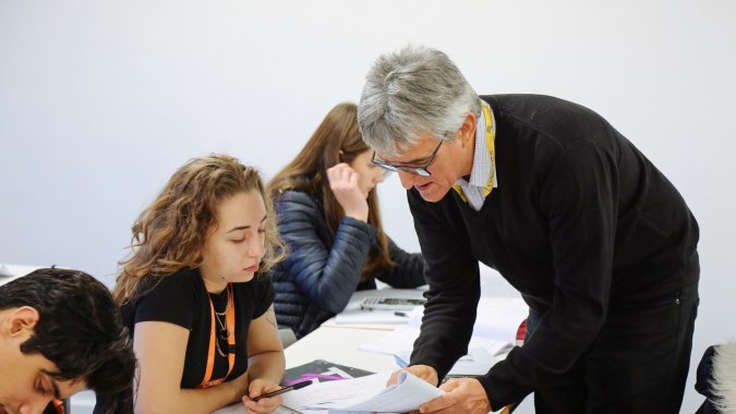 Ein älterer Mann im Anzug unterstützt zwei Schüler bei einem gemeinsamen Projekt am The Sheffield College.
