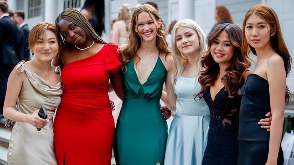 Eine Gruppe von Frauen in bunten Kleidern auf einer Straße vor Gebäuden auf dem Campus der The Stony Brook School.