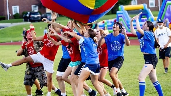 Schüler der The Stony Brook School spielen draußen mit einem großen bunten Fallschirm.