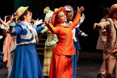 Eine Gruppe von Tänzern in bunten Kostümen führt eine Darbietung auf der Bühne der The Stony Brook School auf.