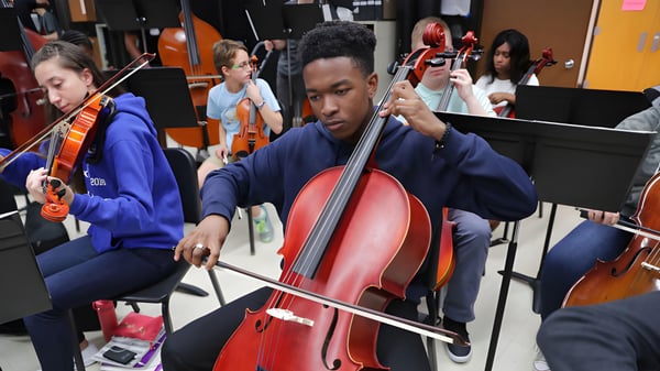 Ein Schüler der The Storm King School spielt konzentriert ein großes rotes Cello in einer Musikprobe.