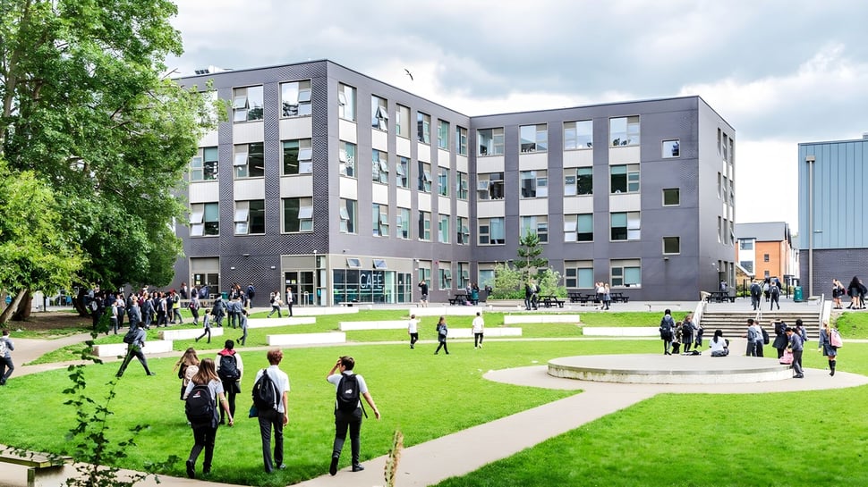 Schüler und Personen auf dem grasbewachsenen Innenhof vor dem modernen Gebäude der The Wren School.