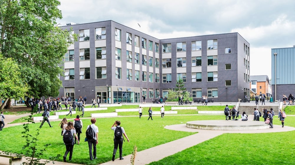 Das moderne mehrstöckige Gebäude der The Wren School mit einem grasbewachsenen Hof und Menschen auf den Wegen.
