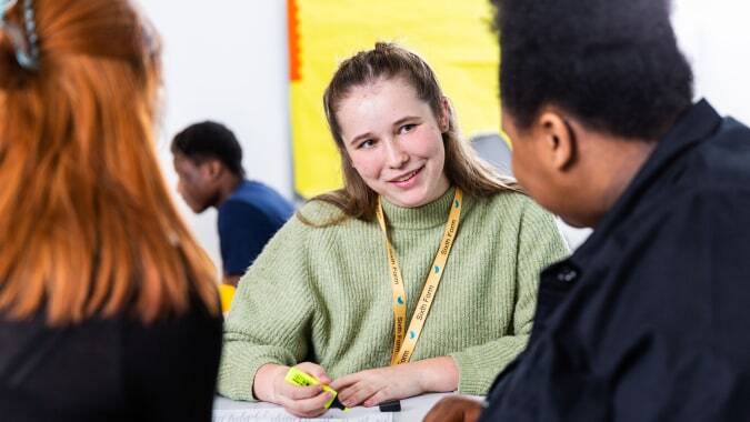 Eine Schülerin der The Wren School unterhält sich in einem farbenfrohen Umfeld mit zwei weiteren Personen.