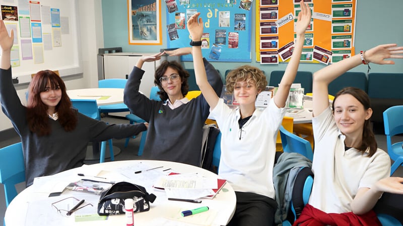 Schüler der The Wren School heben im Klassenraum ihre Hände während einer Unterrichtsaktivität.