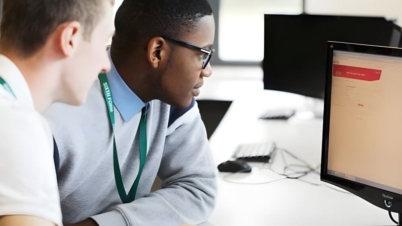 Zwei Personen an einem Bürocomputer auf dem Campus der Theale Green School konzentrieren sich auf den Bildschirm.