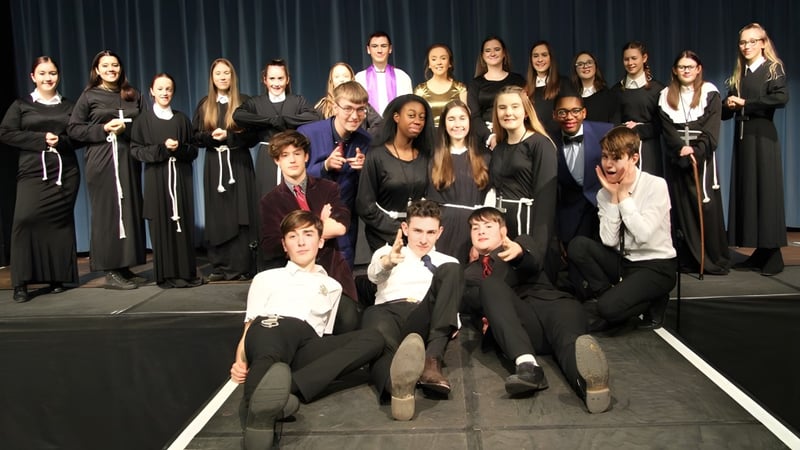 Eine Gruppe von Schülerinnen und Schülern der Theale Green School posiert gemeinsam auf einer Bühne vor einem dunklen Vorhang.