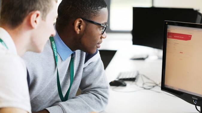 Zwei Personen der Theale Green School arbeiten konzentriert an einem Computer im Büro.