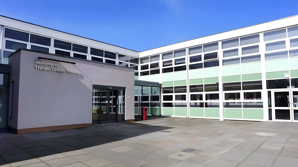 Das mehrstöckige moderne Schulgebäude der Theale Green School mit großen Fenstern unter klarem Himmel.
