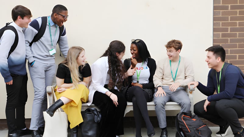 Eine Gruppe Schülerinnen und Schüler der Theale Green School sitzt zusammen in einem Klassenraum mit Backsteinwand und unterhält sich.