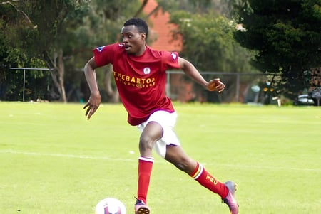 Eine Person läuft auf einem Grasfeld auf dem Campus des Thebarton Senior College vor Bäumen.